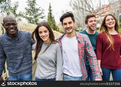Group of multi-ethnic young people laughing together outdoors in urban background. group of people walking together wearing casual clothes