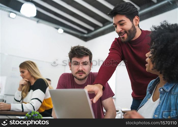 Group of multiethnic creative business people working on a project. Businessman pointing at the monitor screen and showing something to her colleagues. Business concept.