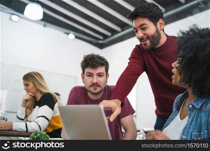 Group of multiethnic creative business people working on a project. Businessman pointing at the monitor screen and showing something to her colleagues. Business concept.