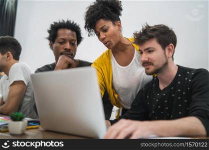 Group of multiethnic creative business people working on a project. Business woman pointing at the monitor screen and showing something to her colleagues. Business concept.