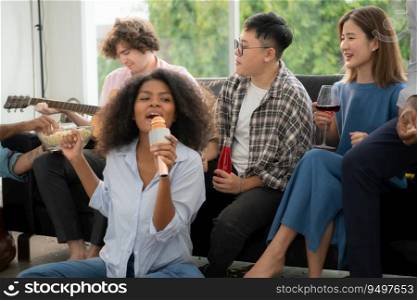 Group of multiethnic friends having fun at party by playing guitar and singing together at home.