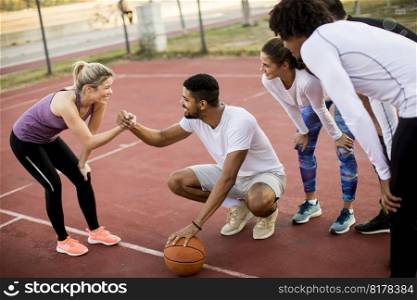 Group of multiethnic young people  playing basketball on court