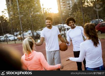 Group of multiethnic young people  playing basketball on court