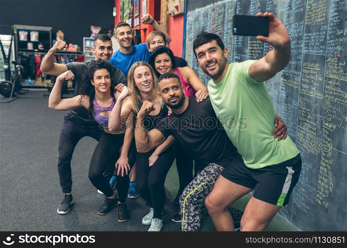 Group of multiracial athletes taking a selfie with the mobile in the gym. Athletes taking a selfie with the mobile in the gym
