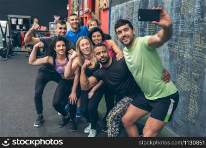 Group of multiracial athletes taking a selfie with the mobile in the gym. Athletes taking a selfie with the mobile in the gym