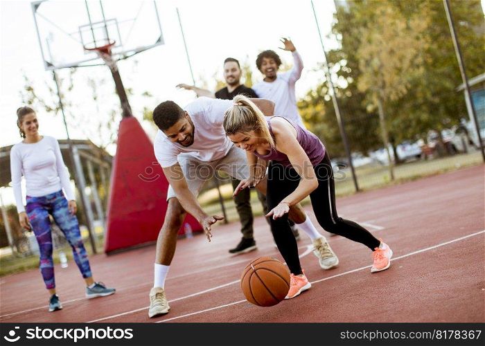 Group of multiracial young people   playing basketball  on court at outdoors