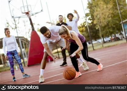 Group of multiracial young people   playing basketball  on court at outdoors