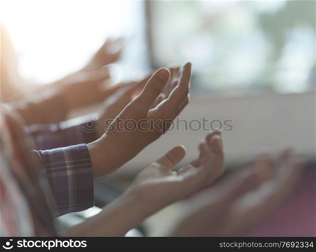 group of muslim people praying namaz in mosque together closeup on hands