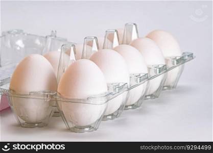 Group of organic white eggs in transparent plastic carton on white background, closeup view, horizontal format.