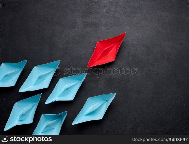 Group of paper boats on a black background.Concept of a strong leader in a team, manipulation of the masses, following new perspectives, collaboration and unification.