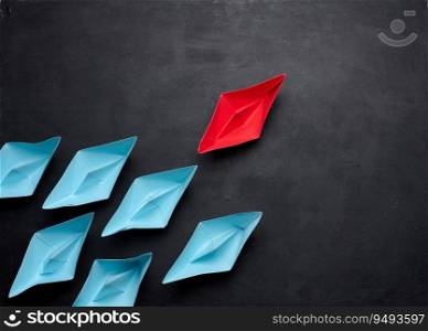 Group of paper boats on a black background.Concept of a strong leader in a team, manipulation of the masses, following new perspectives, collaboration and unification.