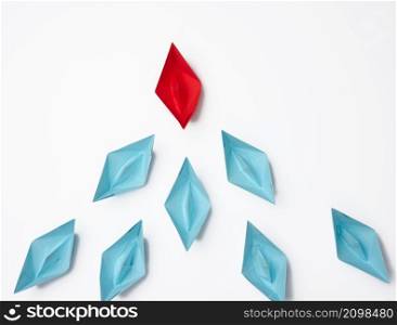 group of paper boats on a white background. concept of a strong leader in a team, manipulation of the masses, following new perspectives, collaboration and unification. Startup