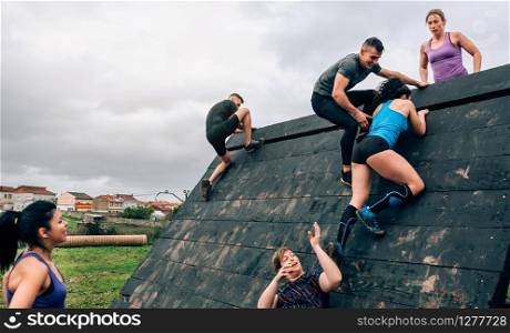 Group of participants in an obstacle course climbing a pyramid obstacle. Participants in obstacle course climbing pyramid obstacle
