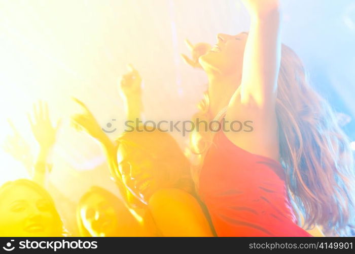 Group of party people - men and women - dancing in a disco club to the music