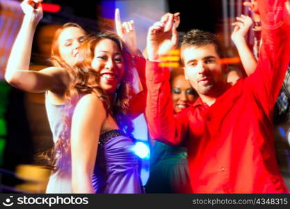 Group of party people - men and women - dancing in a disco club to the music