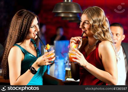 Group of party people with cocktails in a bar or club having fun