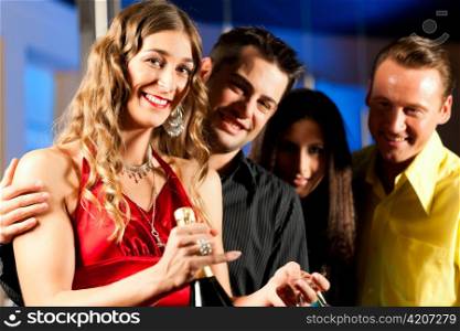 Group of party people with drinks in a bar or club having fun