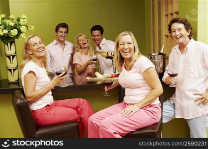 Group of people at a kitchen counter and holding glasses of wine