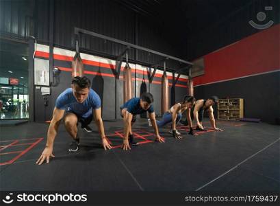 Group of people doing body push up in boxing sport club workout at training gym fitness center. Exercise indoor sport equipment. People lifestyle. Recreation.