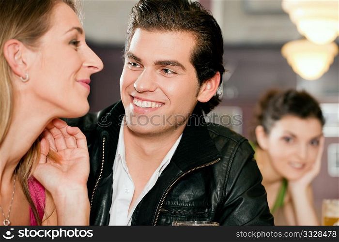 Group of people in a bar or restaurant, one couple flirting very obviously having a lot of fun