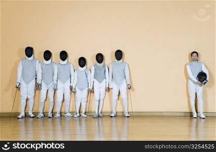 Group of people in fencing costume standing side by side