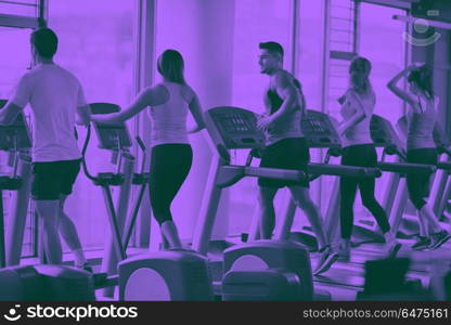 Group of people running on treadmills. group of young people running on treadmills in modern sport gym duo tone