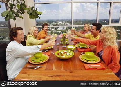 Group of people sitting at the dining table and toasting a drink