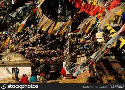 Group of people sitting under prayer flags, Monkey Temple, Katmandu, Nepal