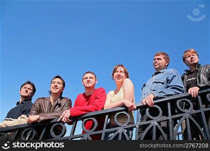 group of people stand leaning on handrail