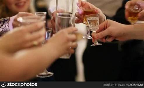 Group of people toasting at a celebration clinking their glasses together in congratulations , close up view of their hands