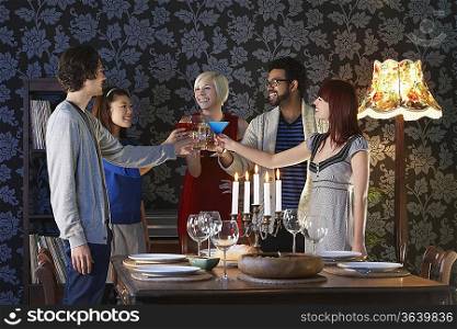 Group of people toasting standing by dining table