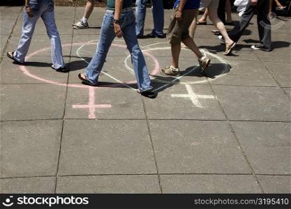 Group of people walking on two female symbols drawn with a heart shape on the road
