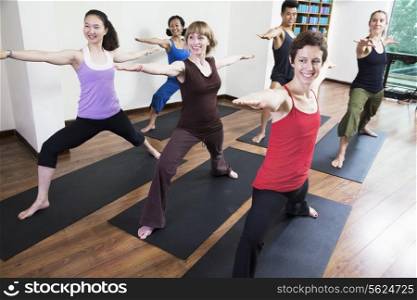 Group of people with arms outstretched doing yoga during a yoga class
