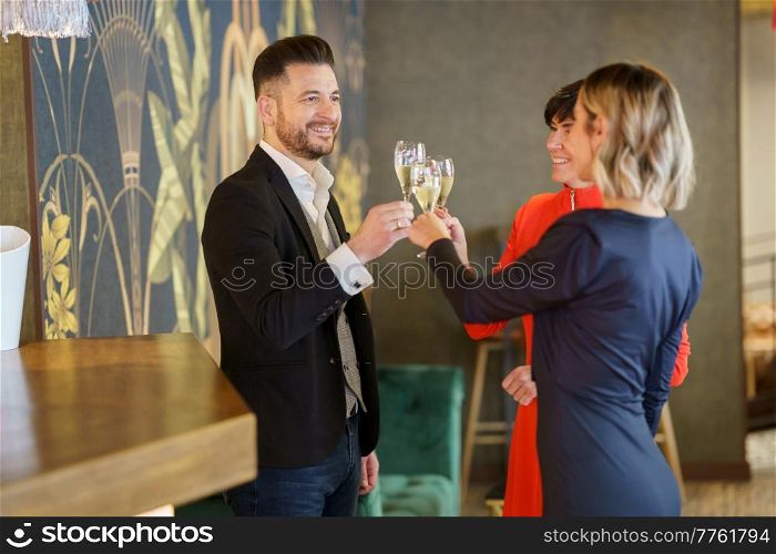 Group of positive well dressed friends clinking glasses with sparkling champagne while celebrating festive event in luxury bar. Happy elegant friends celebrating event in restaurant