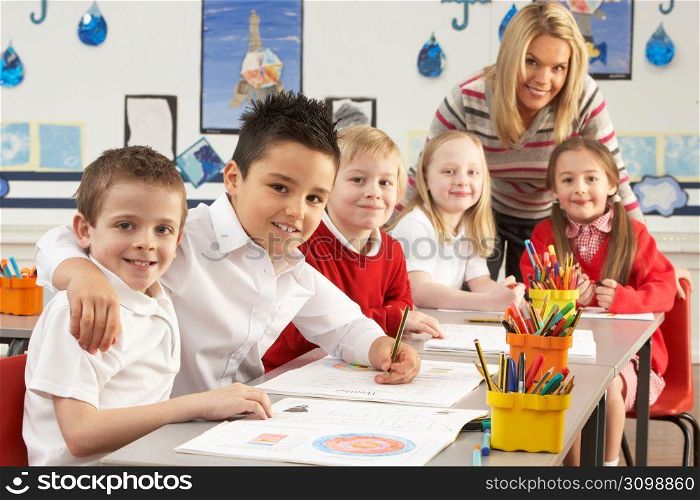 Group Of Primary Schoolchildren And Teacher Working At Desks In Classroom