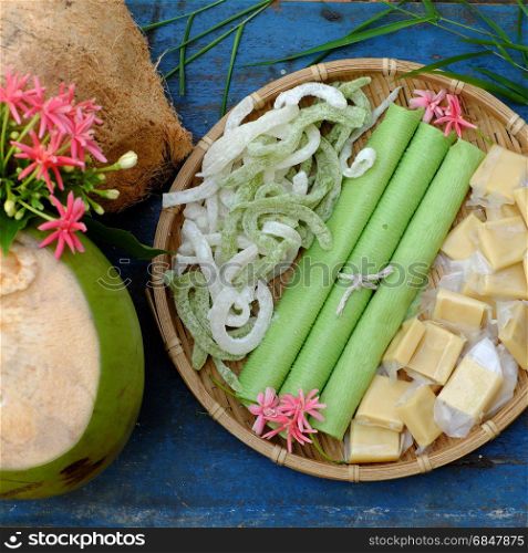 Group of product from coconut with candy, milk rice paper, coconut oil, dark soy sauce, jam or coconut water, are popular Vietnam food, group of snacks and drink on blue background