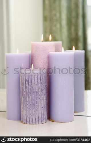 Group of purple candles burning in front of mirror.