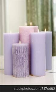 Group of purple candles burning in front of mirror.