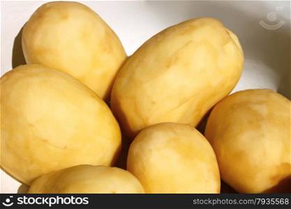 Group of raw yellow peeled potato tubers before boiling close up