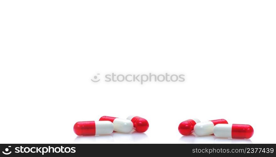 Group of red-white capsule pills on horizontal white background. Prescription drugs. Pharmacy drugstore web banner. Healthcare and medical background. Drug production. Daily dose for love booster.