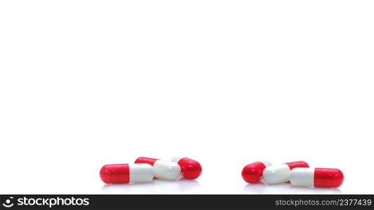 Group of red-white capsule pills on horizontal white background. Prescription drugs. Pharmacy drugstore web banner. Healthcare and medical background. Drug production. Daily dose for love booster.