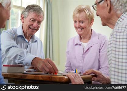 Group Of Retired Friends Playing Board Game At Social Club