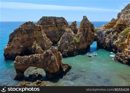 Group of rock formations along coastline of Lagos town, Ponta da Piedade, Algarve, Portugal. All people in motorboats are unrecognizable.