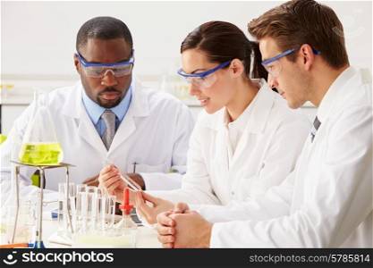 Group Of Scientists Performing Experiment In Laboratory
