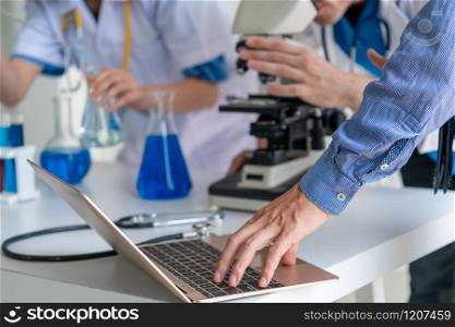 Group of scientists wearing lab coat working in laboratory while examining biochemistry sample in test tube and scientific instruments. Science technology research and development study concept.