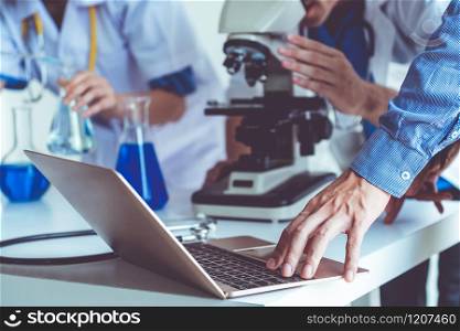 Group of scientists wearing lab coat working in laboratory while examining biochemistry sample in test tube and scientific instruments. Science technology research and development study concept.. Group of scientists working in chemical lab.