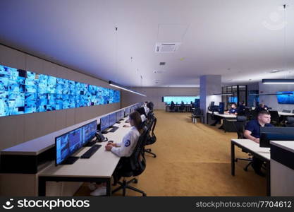 Group of Security data center operators working in a CCTV monitoring room looking on multiple monitors  Officers Monitoring Multiple Screens for Suspicious Activities  Team working on the System Control Room