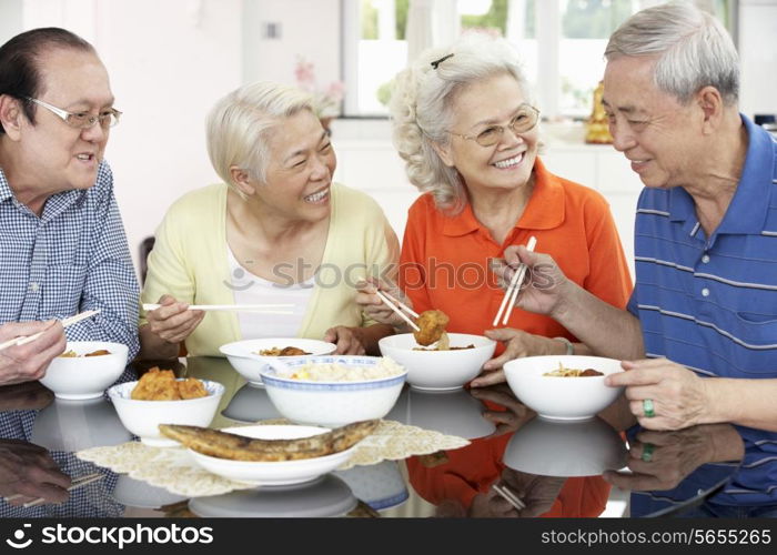 Group Of Senior Chinese Friends Eating Meal At Home