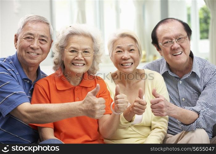 Group Of Senior Chinese Friends Relaxing On Sofa At Home