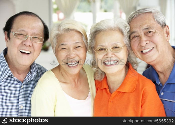 Group Of Senior Chinese Friends Relaxing On Sofa At Home